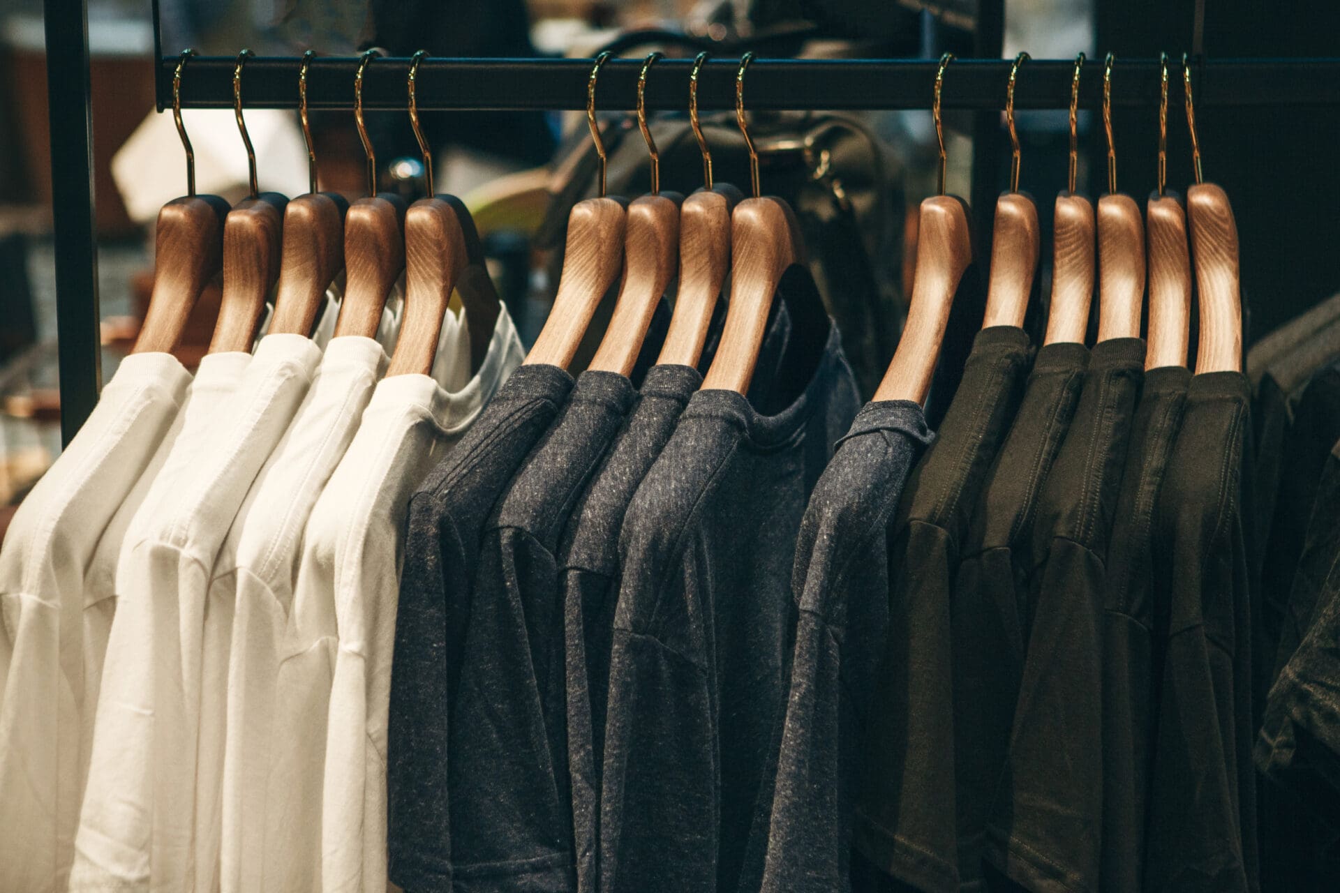 A rack of clothes hanging on wooden hangers.