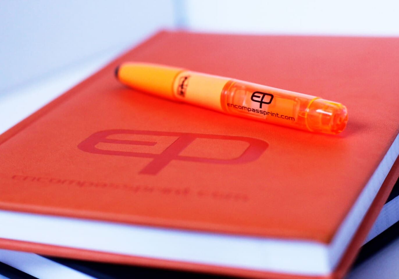 A pen and notebook on top of an orange book.